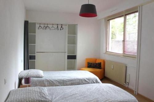ein Schlafzimmer mit zwei Betten und einem orangefarbenen Stuhl in der Unterkunft Spacieux 4 pièces centre de mulhouse in Mulhouse