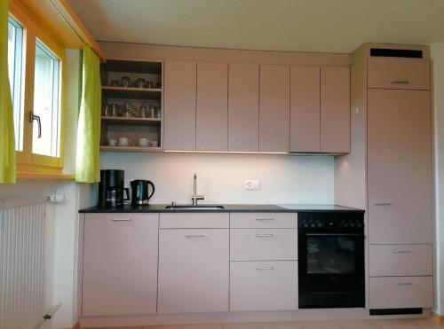 a kitchen with white cabinets and a black dishwasher at Obererli in Hasliberg