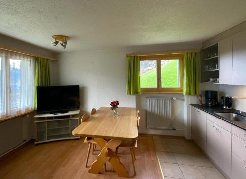 a kitchen with a wooden table and a television at Obererli in Hasliberg