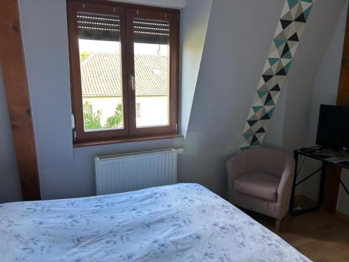 ein Schlafzimmer mit einem Bett, einem Fenster und einem Stuhl in der Unterkunft Les pervenches in Illkirch-Graffenstaden