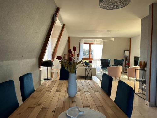 ein Esszimmer mit einer Vase mit Blumen auf einem Holztisch in der Unterkunft Les pervenches in Illkirch-Graffenstaden