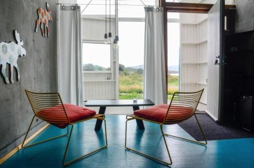 zwei Stühle und ein Tisch in einem Raum mit einem Fenster in der Unterkunft Støkkøya Strandhotell in Hosen