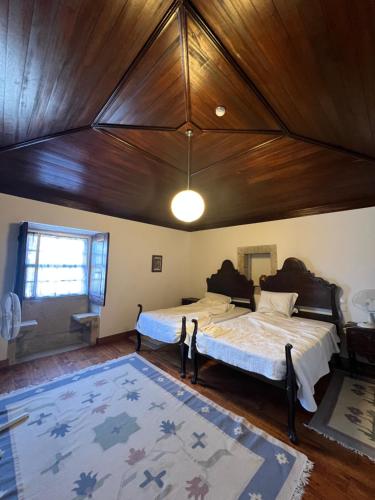 a bedroom with two beds and a wooden ceiling at Casa dos Assentos in Quintiães