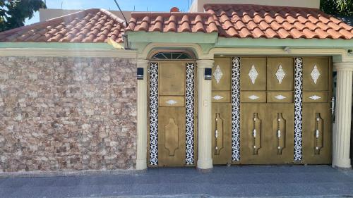 ein Haus mit zwei hölzernen Garagentoren und einer Ziegelmauer in der Unterkunft Increible Casa Con Piscina! in Los Frailes