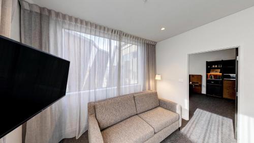 a living room with a couch and a large window at Sudima Queenstown Five Mile in Queenstown