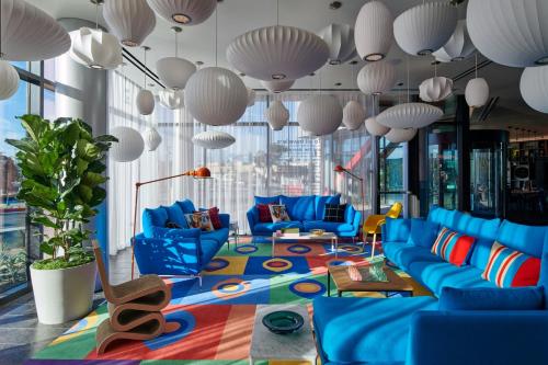 a living room with blue couches and large windows at citizenM Menlo Park in Menlo Park
