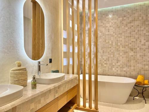 a bathroom with two sinks and a large mirror at Villa AYA - Moderne & Chic in Sraghna