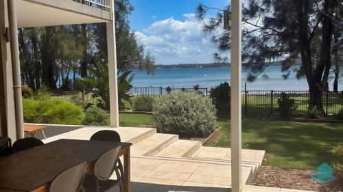 eine Terrasse mit einem Tisch und Blick auf das Wasser in der Unterkunft Pelican Escape Executive Home in Cams Wharf