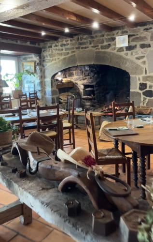 a restaurant with a stone fireplace with tables and chairs at Auberge & Camping Sabatoux in Montusclat