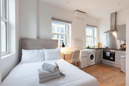 a bedroom with a white bed and a kitchen at Villas Apart Hotel in London
