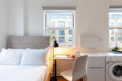a bedroom with a bed and a desk with a washing machine at Villas Apart Hotel in London