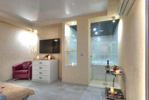a bedroom with a bathroom with a tub and a television at Alex Hotel on Bogatyrsky in Saint Petersburg