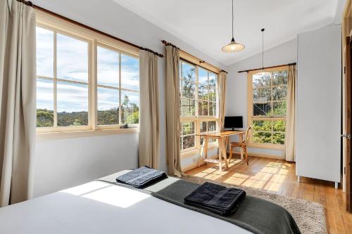 温特沃斯瀑布Graylyn House Wentworth Falls Blue Mountains的一间卧室配有床、窗户和书桌