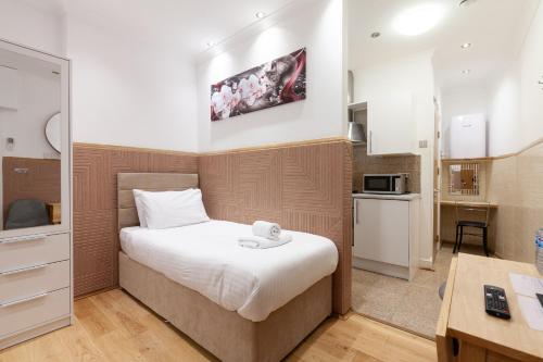a small bedroom with a bed and a kitchen at Argyle Apart Hotel in London