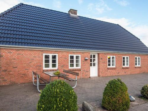 a red brick house with a bench and a table at 5 person holiday home in Rømø in Toftum