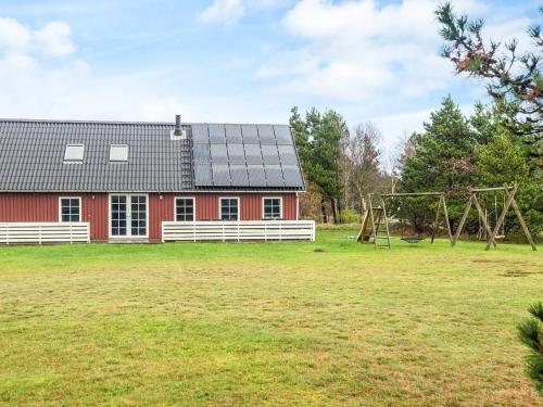 eine rote Scheune mit einem Spielplatz auf dem Feld in der Unterkunft Luxury Retreat with Pool - By Traum Ferienwohnungen in Toftum