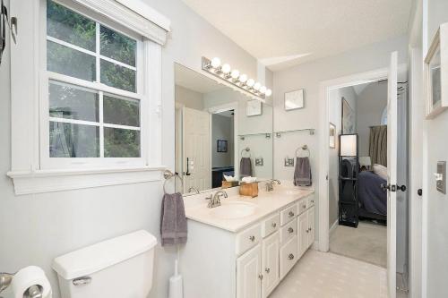 Un baño blanco con lavabo y espejo. en Majestic Home in Summer Oaks, en Apex