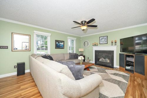 Majestic Home in Summer Oaks في أبيكس: غرفة معيشة مع أريكة ومروحة سقف