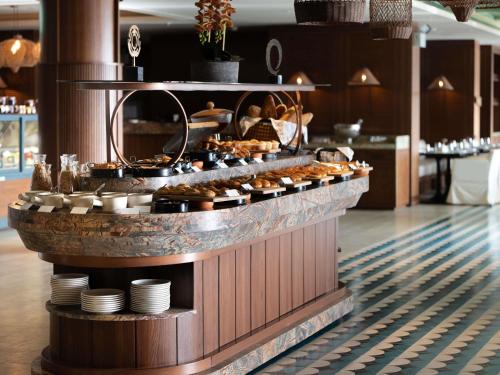 a buffet in a restaurant with food on a counter at The Bodrum Hotel Yalıkavak - MGallery Collection in Yalıkavak