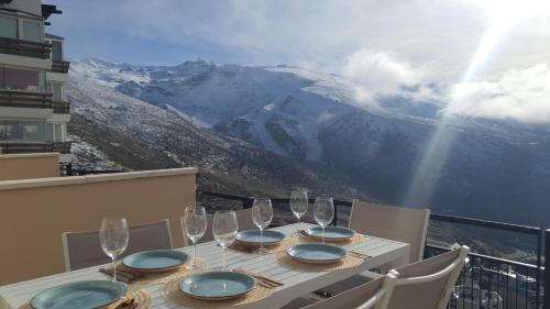 a table with wine glasses on a balcony with mountains at SnowGranada Los Valles Daniela House in Monachil
