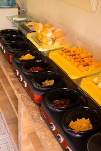 un comptoir avec plein de nourriture dans des bols noirs dans l'établissement Pousada Praia Dos Encantos, à Japaratinga