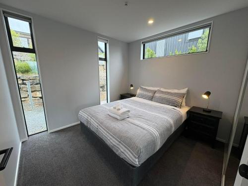 Un dormitorio con una cama y dos ventanas en Glenvue 2 Bed, en Lake Tekapo