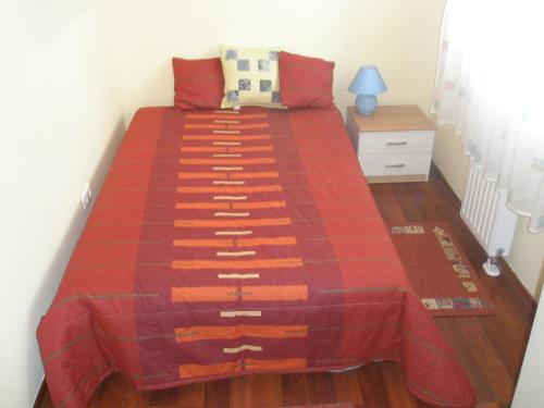 a bedroom with a bed with a red comforter at Club218 Relax Family Apartman in Siófok