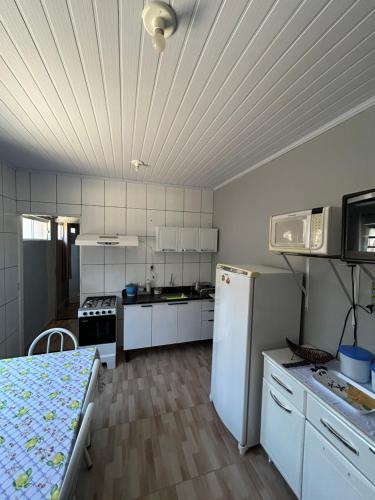 eine Küche mit einem weißen Kühlschrank und einem Tisch in der Unterkunft casa cristal in Alto Paraíso de Goiás