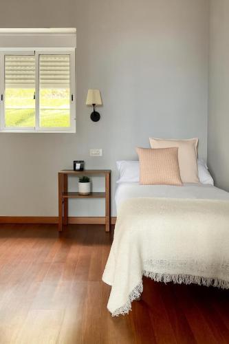 a bedroom with a bed and a table and two windows at Casa Musiú: vistas únicas y excelente ubicación! in Las Nieves