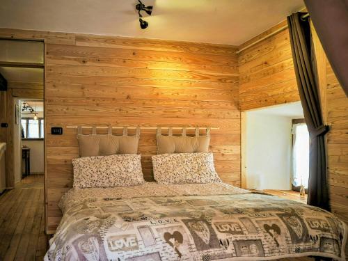 ein Bett in einem Zimmer mit einer Holzwand in der Unterkunft Stone Cabin With Views Over Balme Valley in Alo di Stura