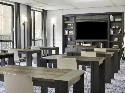 海牙Mövenpick Hotel The Hague的一间带桌子和平面电视的用餐室