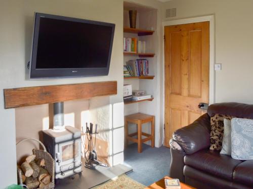 a living room with a flat screen tv above a fireplace at Breasty Haw in Grizedale