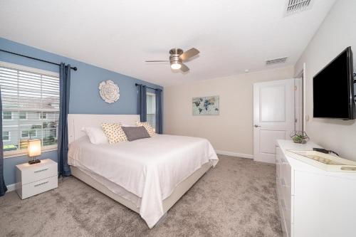 a bedroom with a white bed and a flat screen tv at 4830FA TOWNHOUSE 4 BEDROOMS & 3 BATHROOMS + POOL in Kissimmee