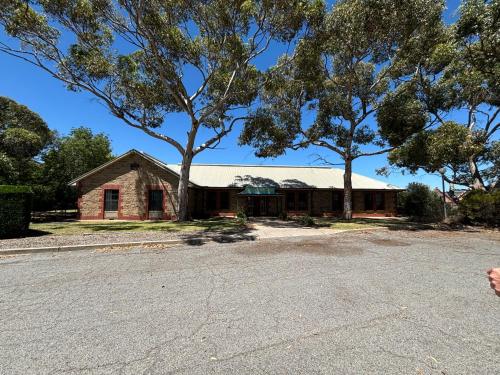 an old brick house with trees in front of it at Barossa Backpackers in Tanunda