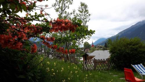 un árbol con flores rojas en un patio con una casa en Ferienwohnung Ritz, en Ernen
