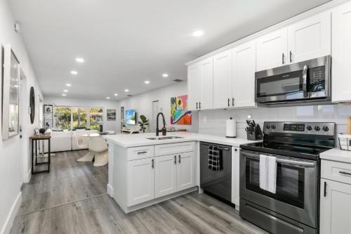 a kitchen with white cabinets and stainless steel appliances at Modern Miami Oasis with Pool & Water View in North Miami