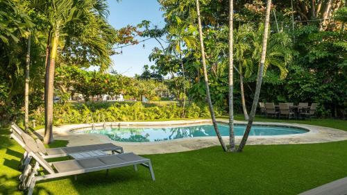 a bench next to a swimming pool with palm trees at Modern Miami Oasis with Pool & Water View in North Miami