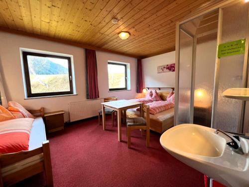 une chambre avec un lit et un lavabo, et un lit et une table dans l'établissement Schwoichbauer, à Saalbach-Hinterglemm
