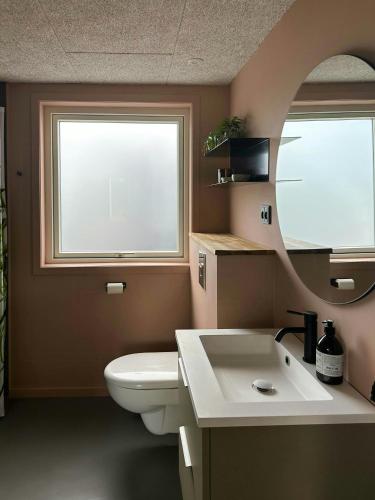 łazienka z toaletą, umywalką i lustrem w obiekcie Summer House Near The Beach At Grønninghoved w mieście Binderup Strand