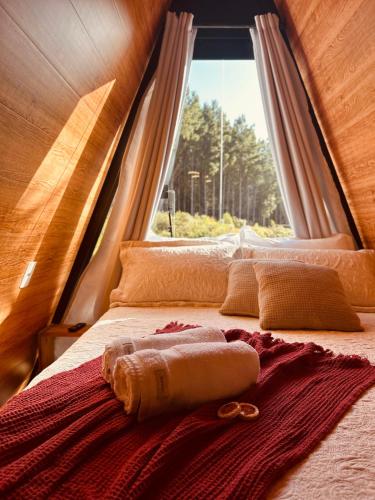 a bed with a towel on it in front of a window at Chalé Araucárias Cambará do Sul in Cambará