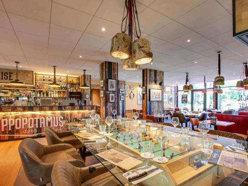 a restaurant with a glass table and chairs at Novotel Bordeaux Mérignac in Mérignac