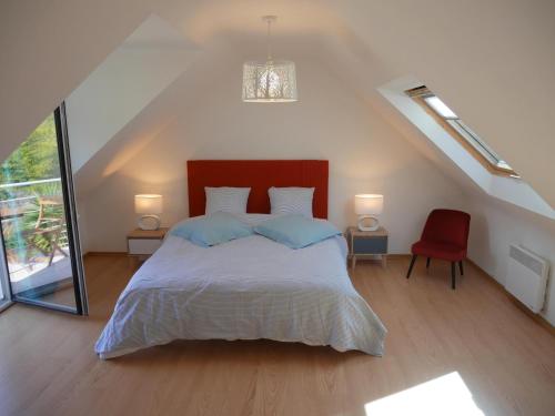 a bedroom with a bed and a red chair at Holiday home with partial sea view, Douarnenez in Tréboul
