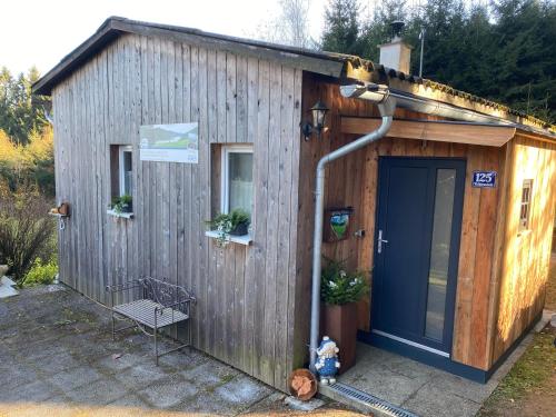 - un petit bâtiment en bois avec une porte et un banc dans l'établissement Herzhütte Für Zwei, à Vichtenstein