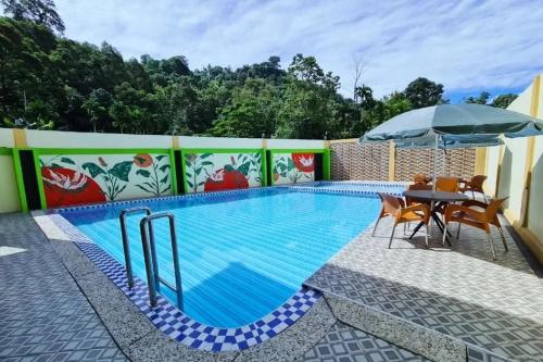 einen Pool mit einem Tisch und einem Sonnenschirm in der Unterkunft Lenarda hotel in Nggorang