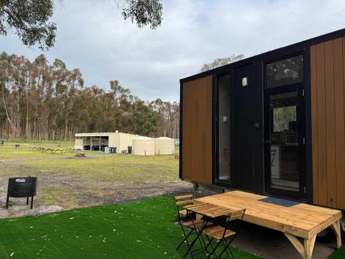 a house with a wooden table and a bench at Bush Hideaway X by Tiny Away in Comaum