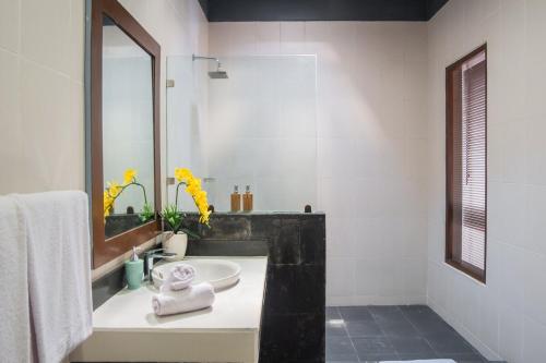 a white bathroom with a sink and a mirror at Tranquil 2BR Villa, Near Canguu and Pererenan in Tumbak Bayuh