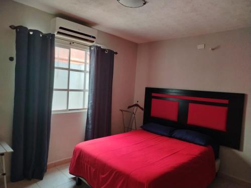Un dormitorio con una cama roja y una ventana. en Bonaterra, en El Jobo