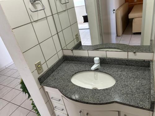 ein Badezimmer mit Waschbecken und Spiegel in der Unterkunft Apartamentos Aquarius Flat in Caldas Novas