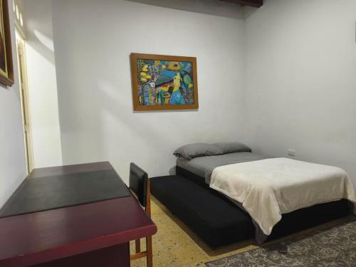 a room with two beds and a table and a painting at Casa Prado Centro in Medellín