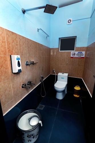 a bathroom with a toilet and a tv on the wall at Narmada pool villa kavery in Perintalmanna